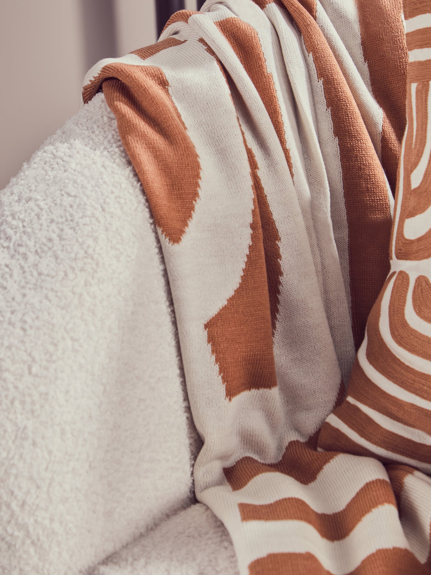 Close-up of a brown and white patterned blanket draped over a textured surface.