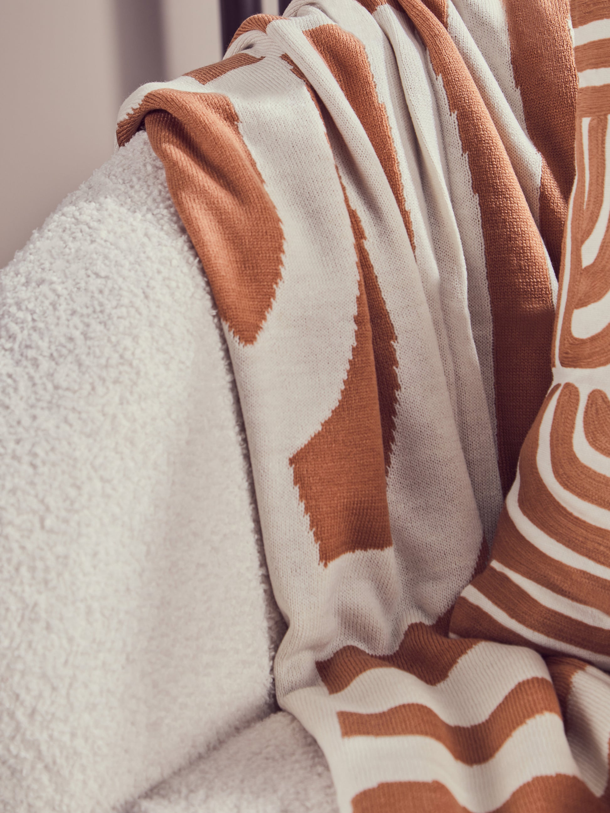 Close-up of a brown and white patterned blanket draped over a textured surface.
