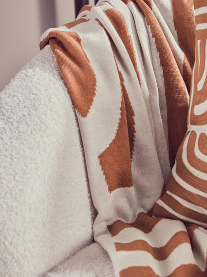 Close-up of a brown and white patterned blanket draped over a textured surface.