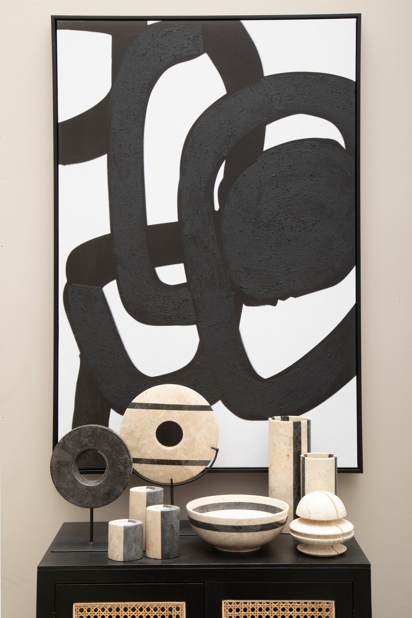 Abstract black and white artwork on a wall with decorative items below.
