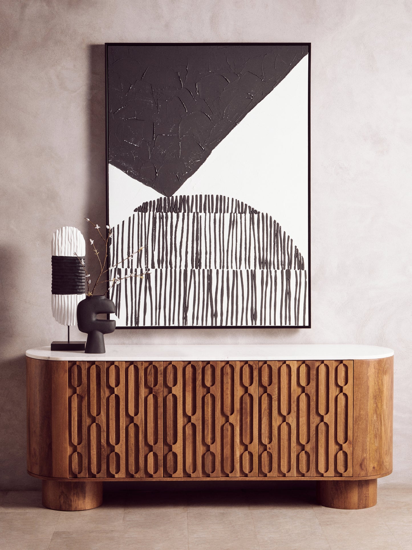 Wooden cabinet with abstract art and decorative lamp against a neutral wall