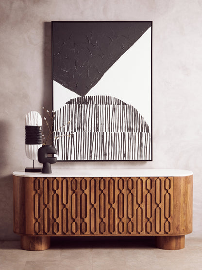 Wooden cabinet with abstract art and decorative lamp against a neutral wall