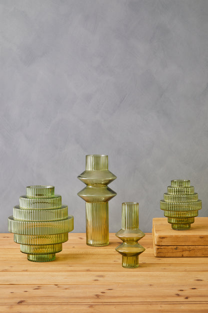 Set of green glass vases on a wooden surface with a gray background