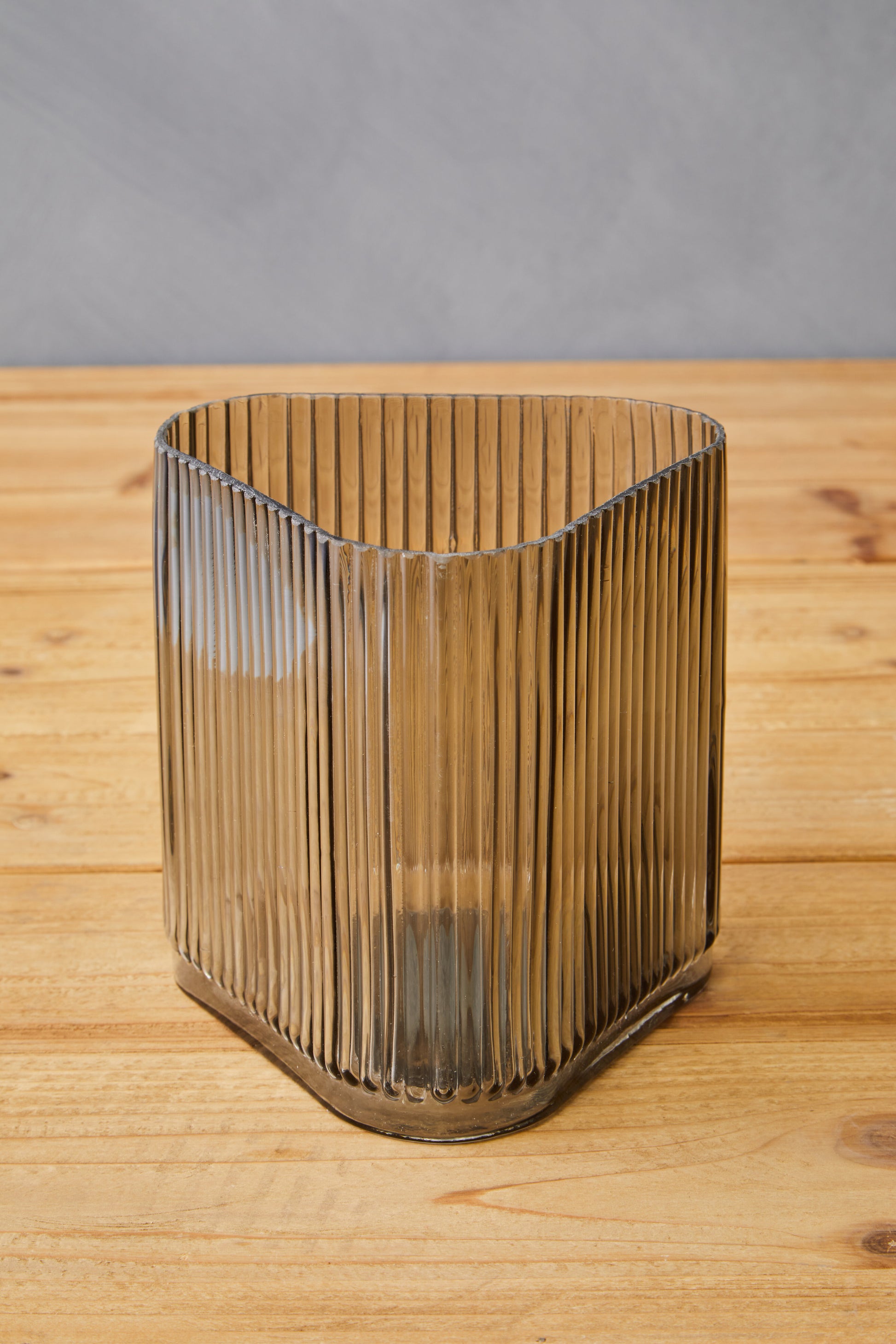 Glass vase with ribbed design on a wooden surface