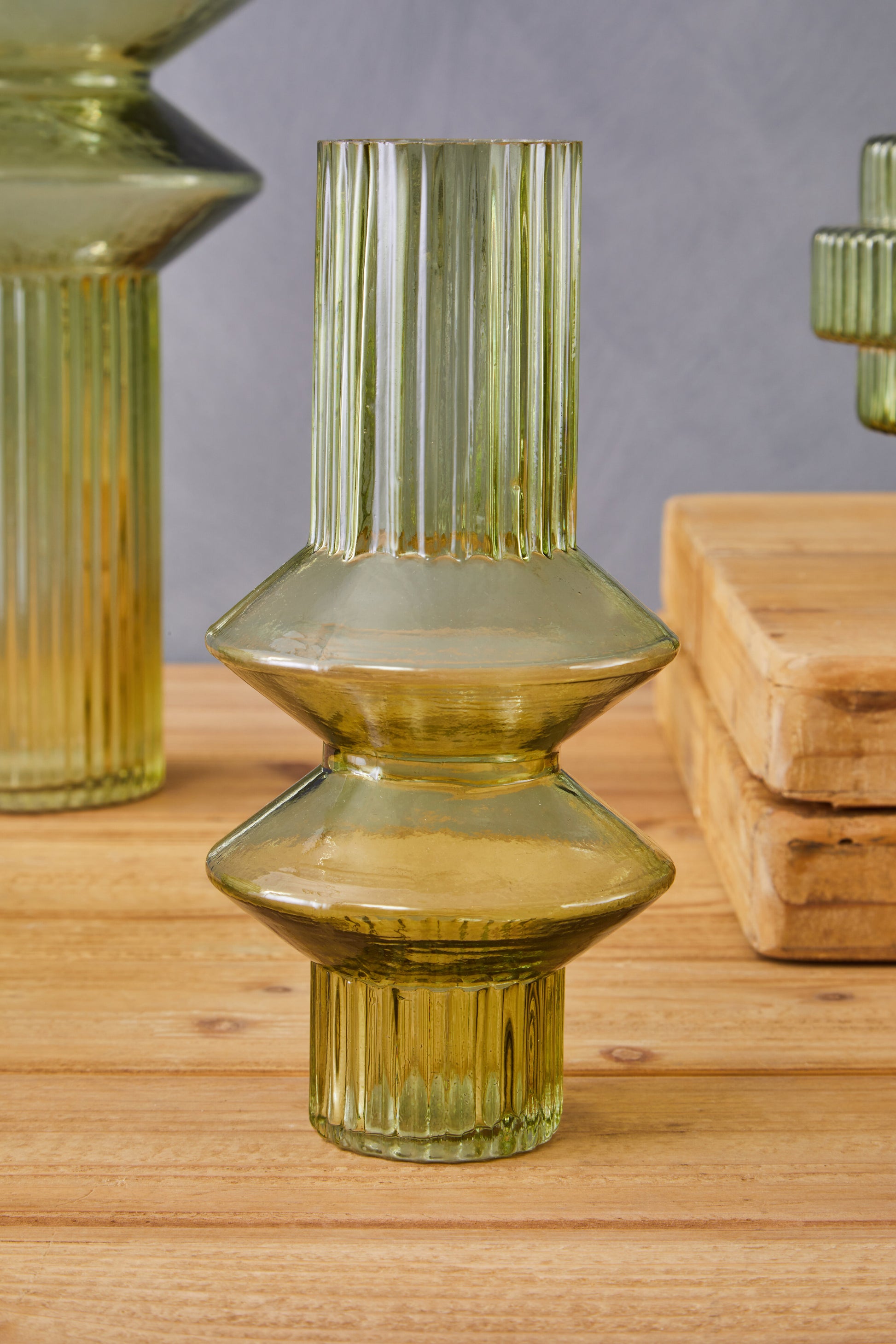 Green glass vase with textured design on a wooden surface