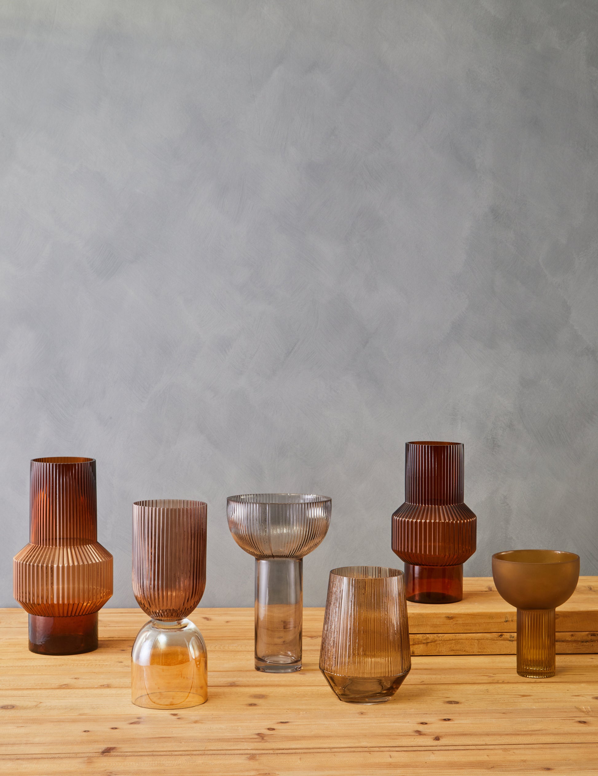 Set of glass vases on a wooden surface with a gray background