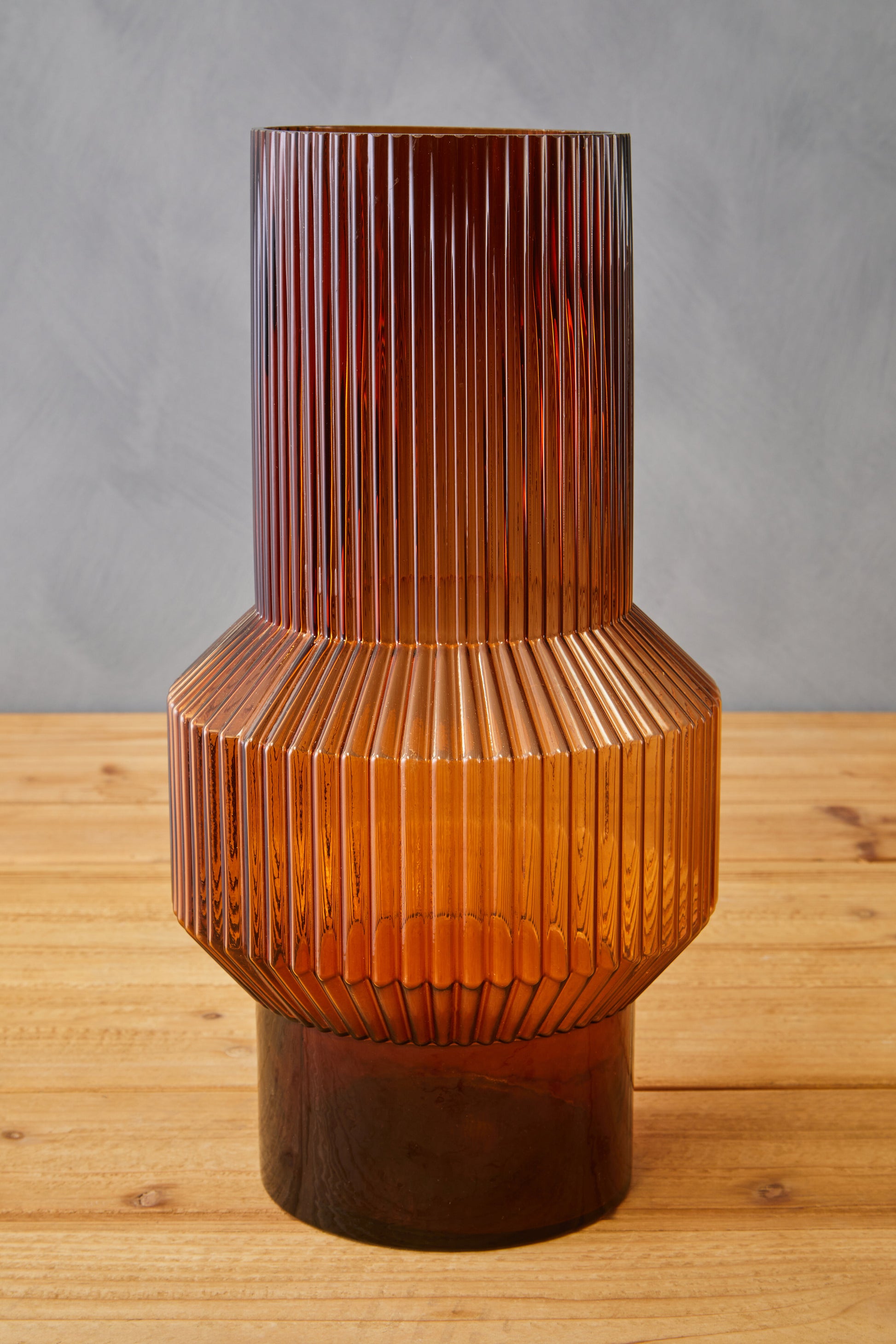 Brown textured vase on a wooden surface with a gray background
