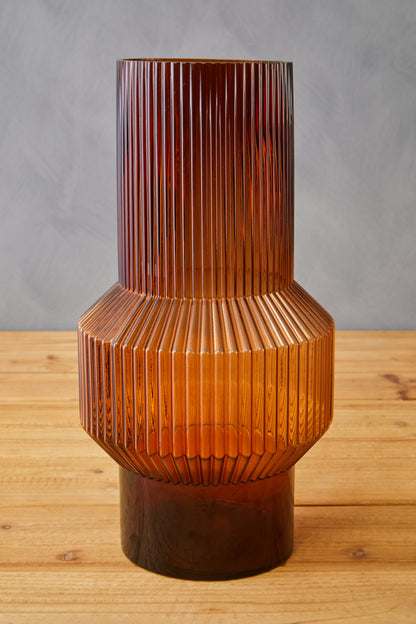 Brown textured vase on a wooden surface with a gray background