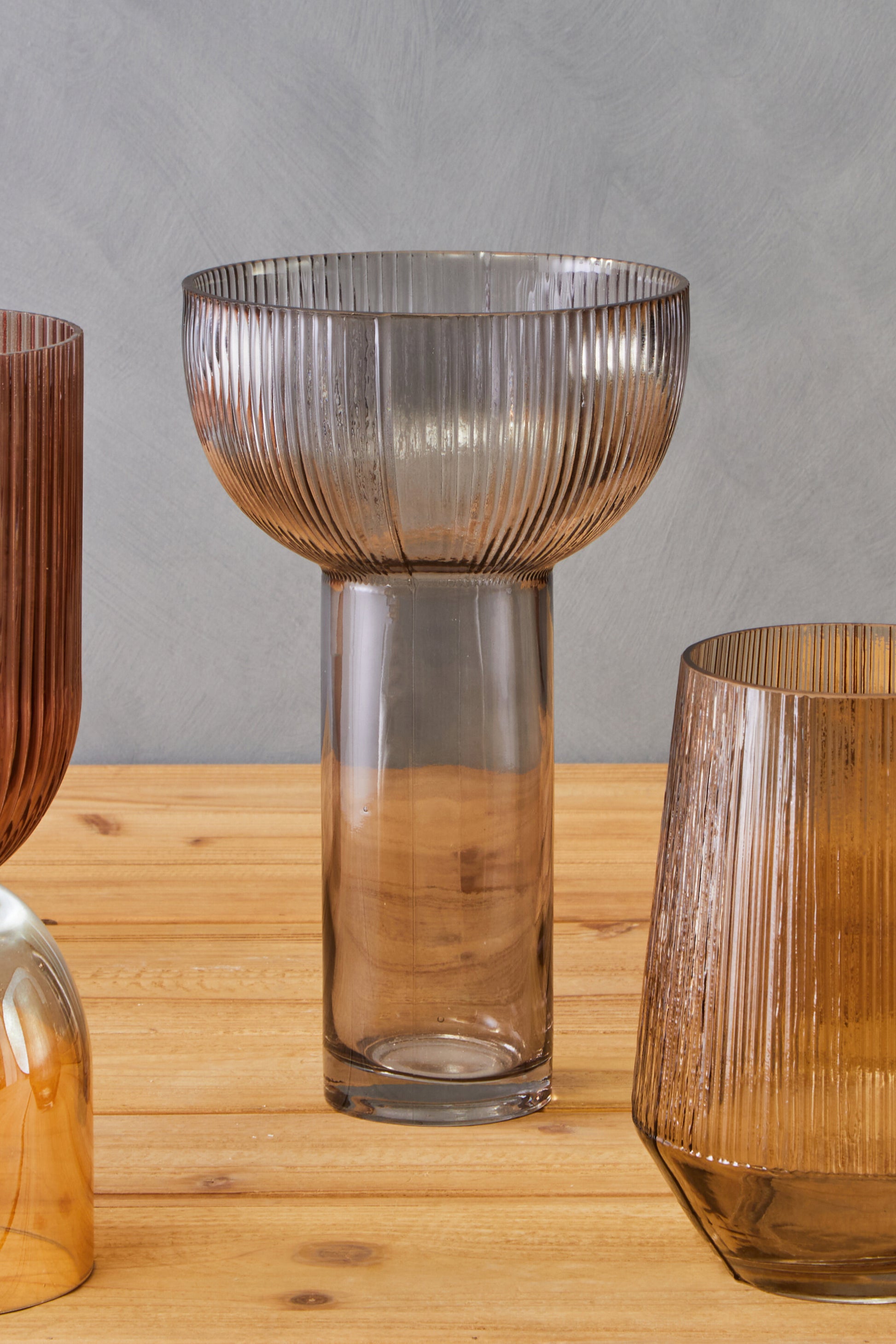 Set of glass vases on a wooden surface with a gray background