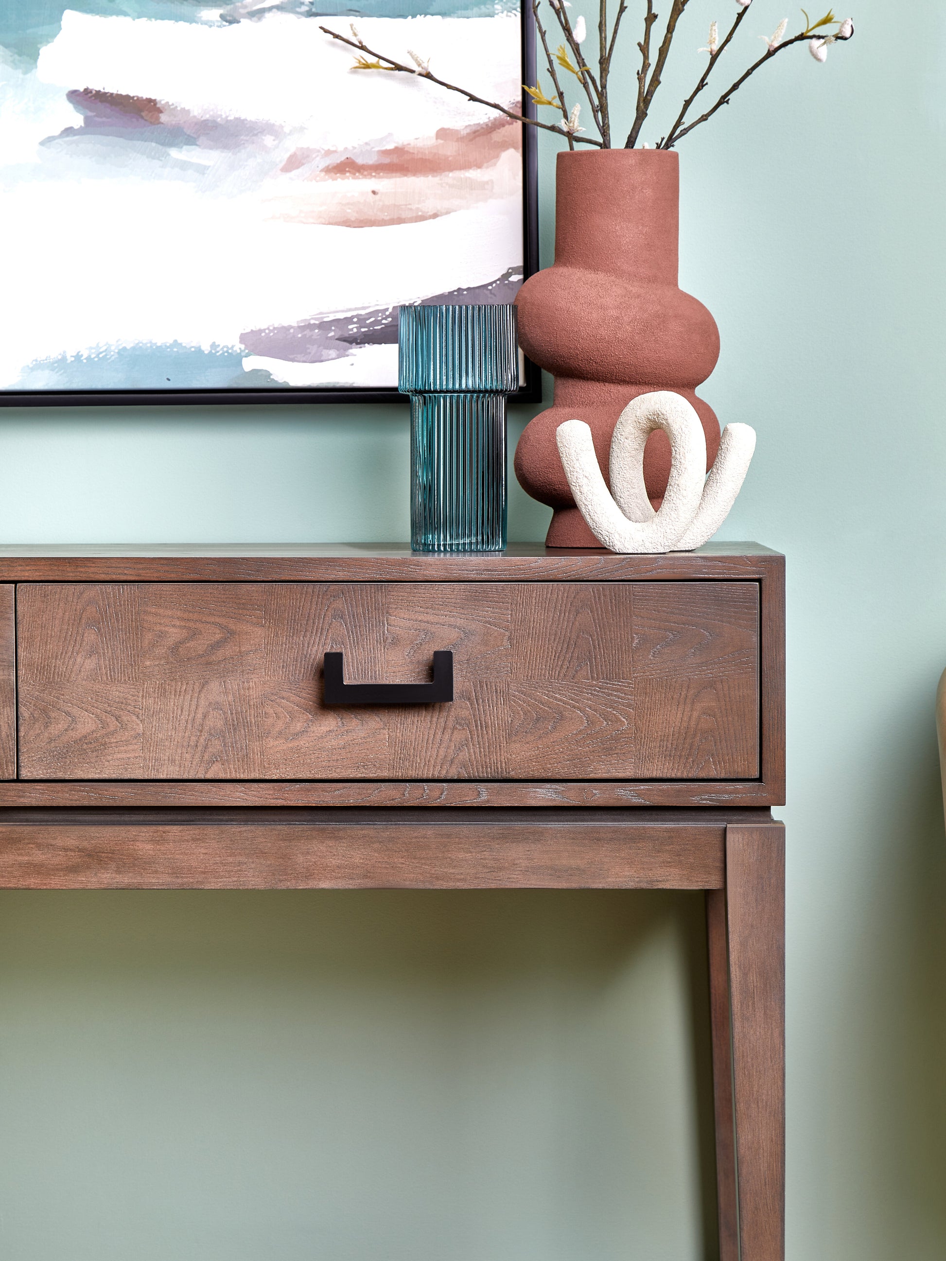 Wooden console table with decorative items against a light green wall
