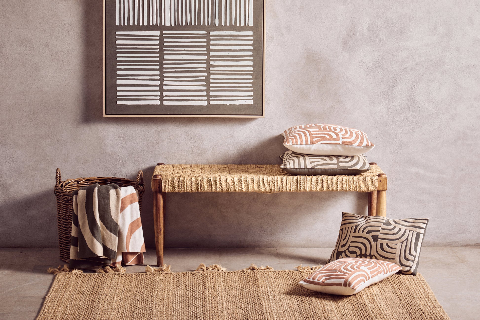 Wicker bench with patterned cushions against a gray wall