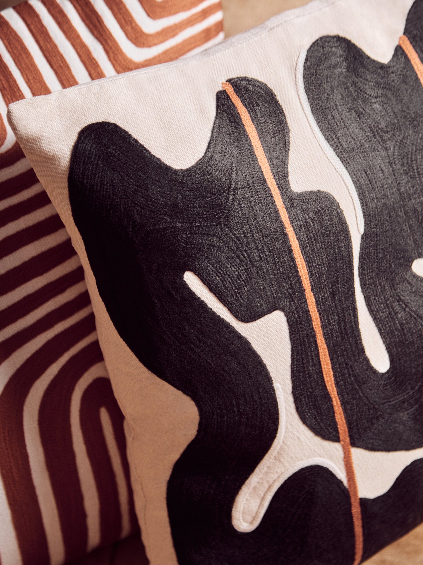 Decorative pillow with abstract black and white design on a striped background