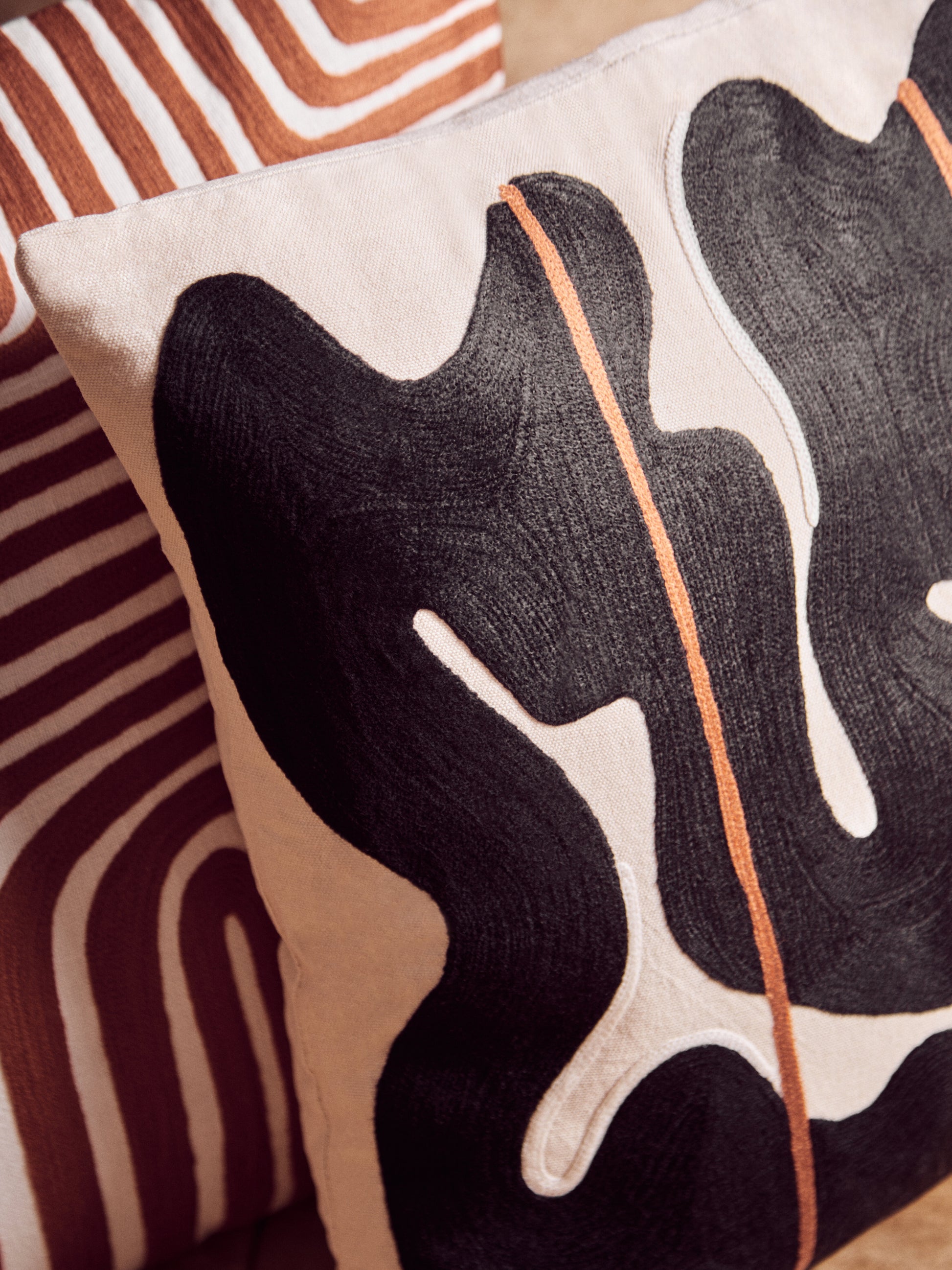 Decorative pillow with abstract black and white design on a striped background